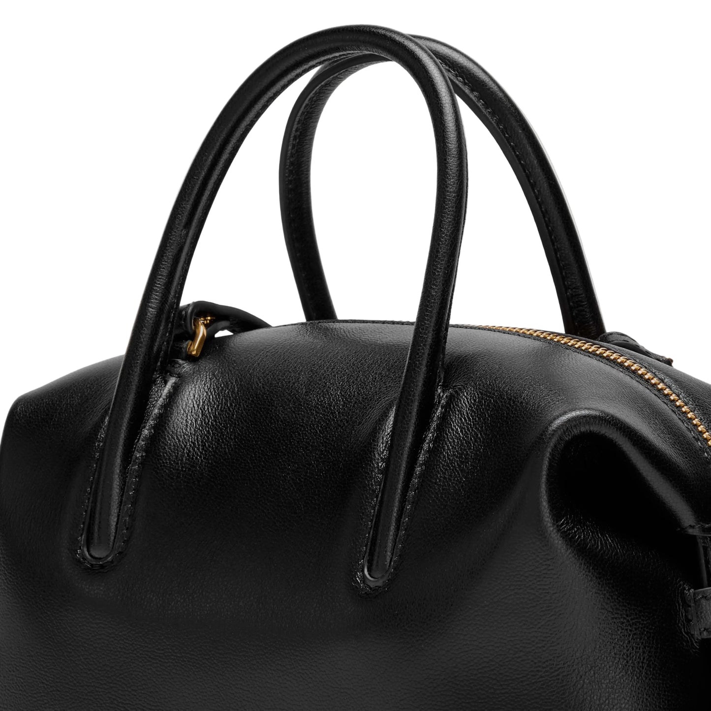 Close-up of a black leather handbag with gold zipper on a light background